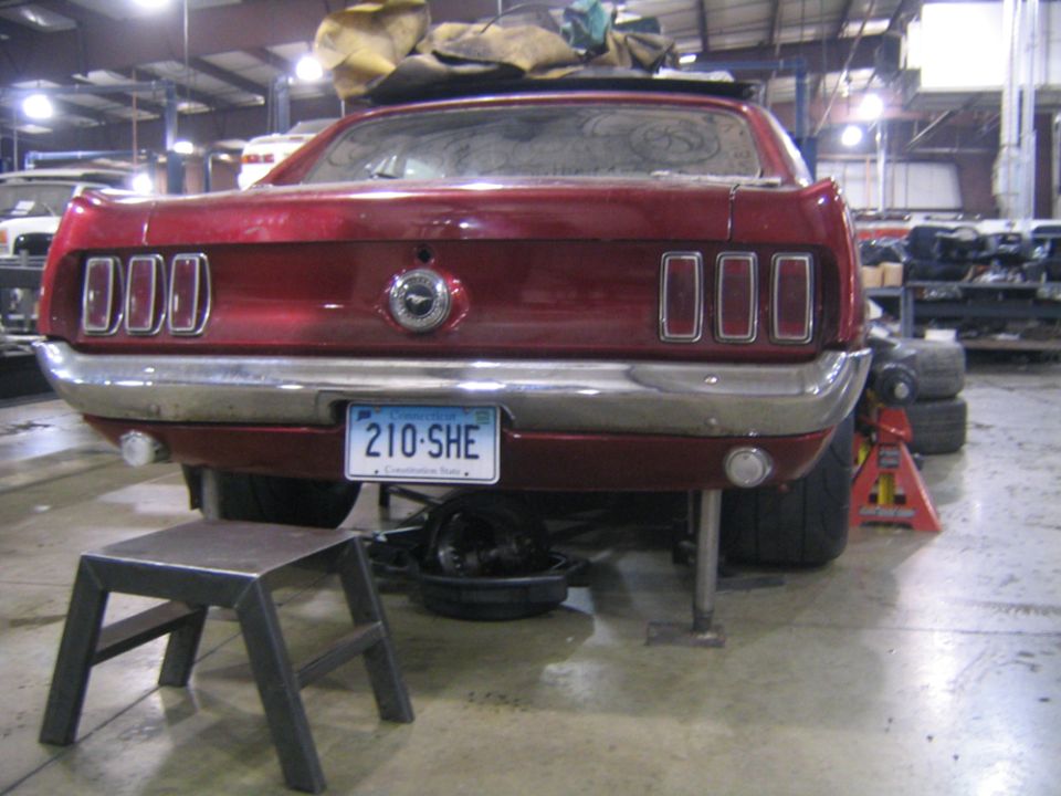 Red 1969 Ford Mustang rear with triple taillights and chrome bumper