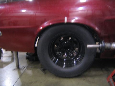 1969 Ford Mustang - Close-up of a car's rear wheel and fender, showing a wide tire and black rim.
