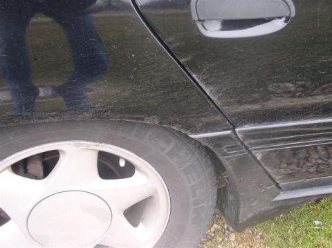 1997 Ford Taurus - Close-up view of the rear quarter panel and wheel of a black 1997 Ford Taurus.
