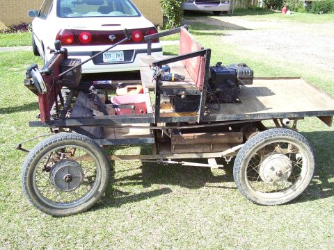 1992 Ford Bronco - This homemade vehicle has a small engine and a flatbed, with a white sedan behind it.