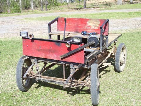 1992 Ford Bronco - This homemade vehicle features a red body, wooden benches, and exposed mechanical components.