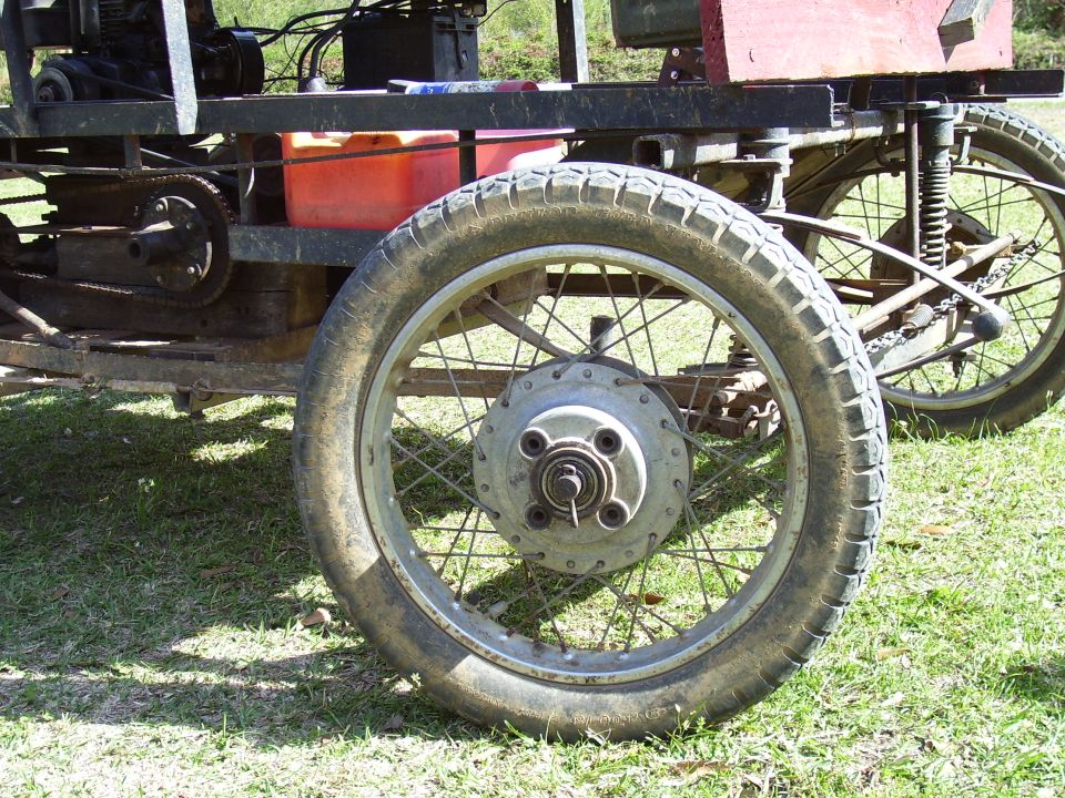 Close-up of a spoked wheel and tire on a custom-built vehicle, with another wheel visible in the background