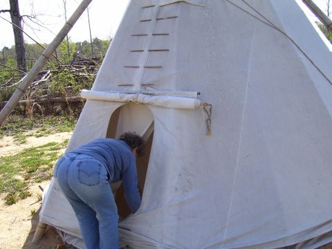1992 Ford Bronco - A person enters a teepee in an outdoor setting with trees and debris in the background.