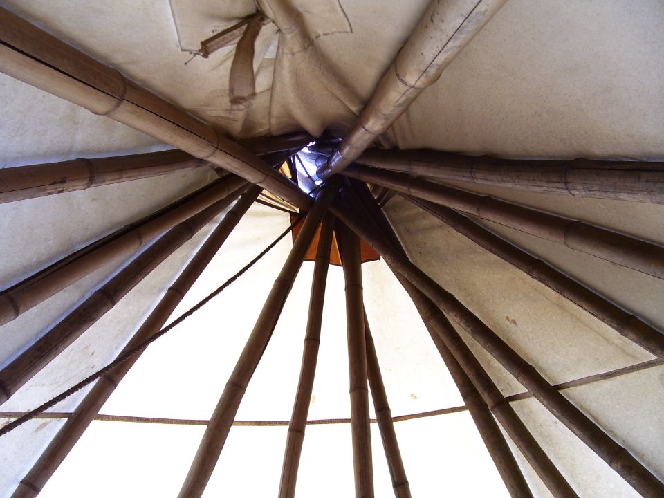 View from inside a teepee looking up at the wooden poles and canvas roof