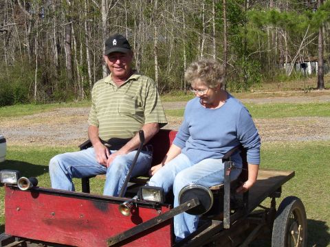 1992 Ford Bronco - A man and a woman sit in a homemade go-kart outdoors.