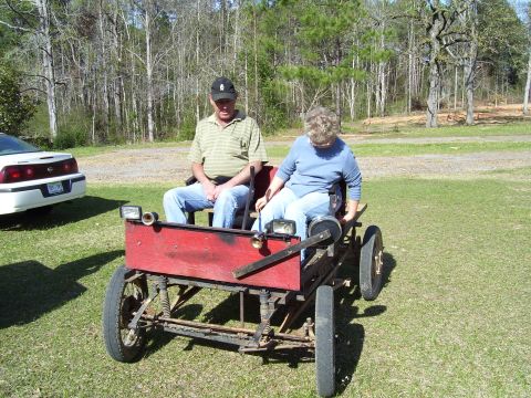 1992 Ford Bronco - Two people sit in a homemade red buggy with a white car nearby.