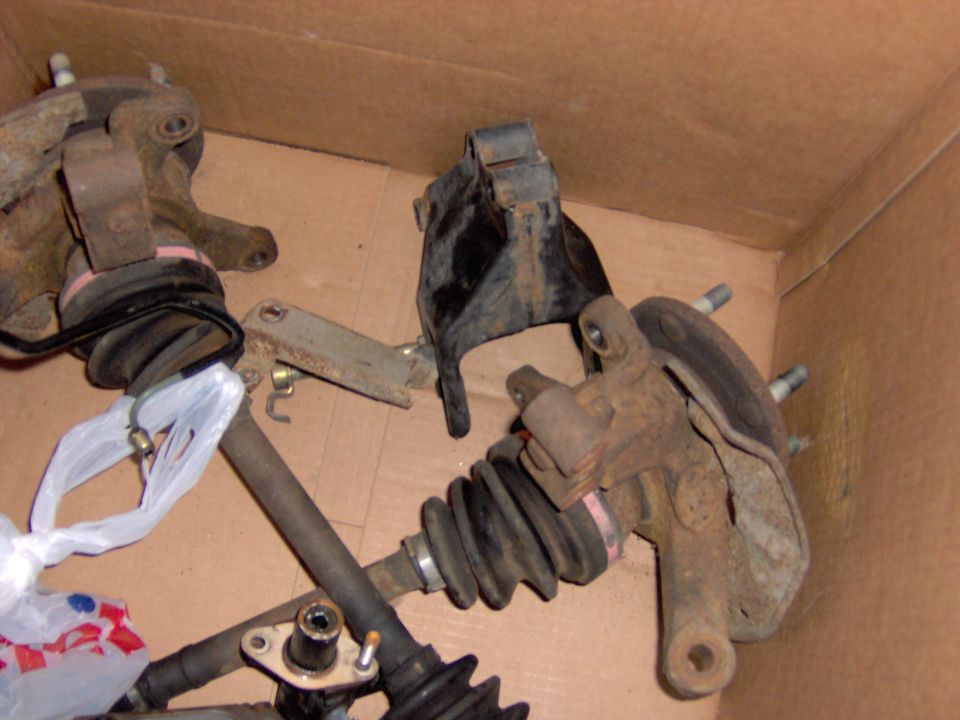 Box of used front suspension parts including steering knuckles, hubs, calipers and CV axles