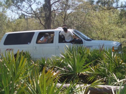 2000 Ford Excursion - White Ford Excursion appears stuck in dense vegetation with occupants visible through the windows.