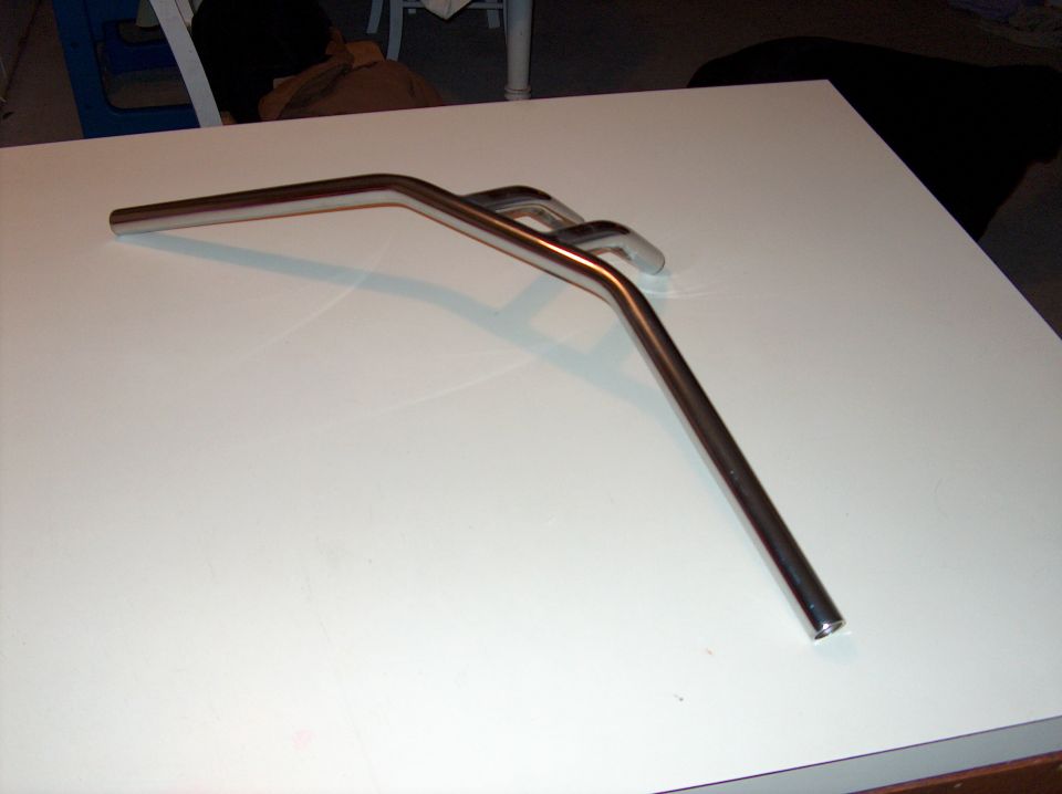 Chrome motorcycle handlebars on a white surface