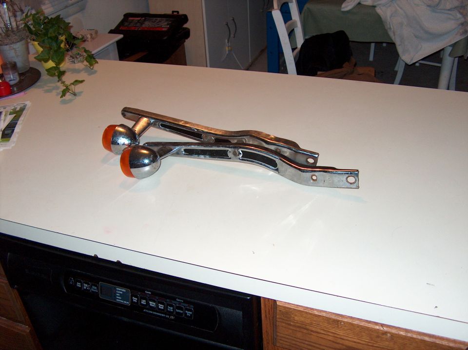 Pair of chrome motorcycle brackets with orange-tipped ball ends on a kitchen counter