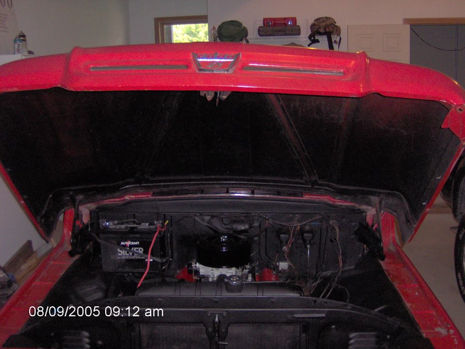 Red pickup truck with hood open, showing engine bay. Visible grille details suggest a 1956 model