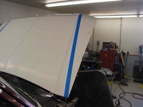 1981 Ford Bronco - Car hood with blue tape in a workshop setting.