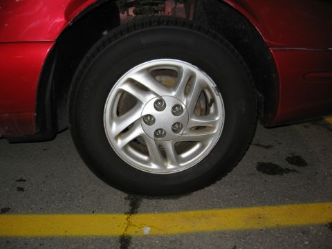 1995 Ford Thunderbird - Close-up of a red car's wheel and fender, showing a silver five-spoke rim.