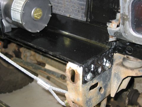 1981 Ford Bronco - A winch motor is bolted to a custom bracket on the vehicle's frame, with steel cables extending from it.