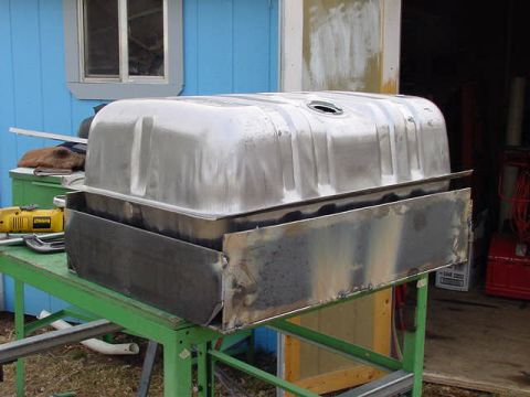 1981 Ford Bronco - A bare metal fuel tank is shown with a custom-made skidplate, resting on a workbench.