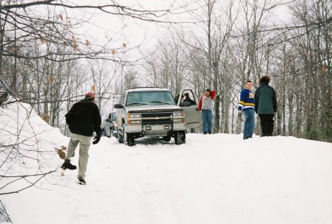 2000 Chevrolet Tahoe - Several people gather around a Chevrolet pickup truck stuck in the snow during winter.