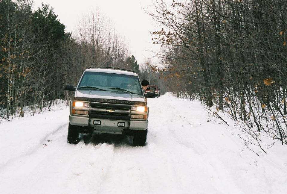 1995 Chevrolet Tahoe driving on a snow-covered road with another SUV behind it