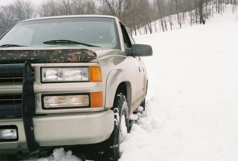 2000 Chevrolet Tahoe - Silver Chevrolet Tahoe with brush guard stuck in deep snow on a wooded hillside.