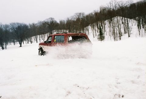 2000 Chevrolet Tahoe - SUV driving through a snowy landscape with trees in the background.