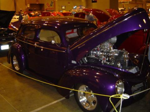 1979 Ford Bronco - A custom purple hot rod with its hood open, revealing a polished engine, is displayed indoors.
