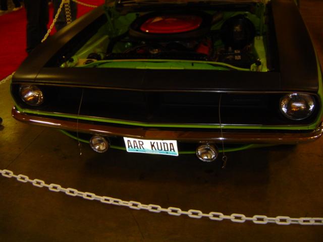 Front view of a green and black muscle car with hood open, showing engine