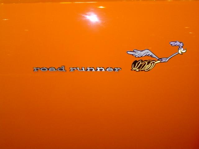 Orange car with 'road runner' text and cartoon bird emblem