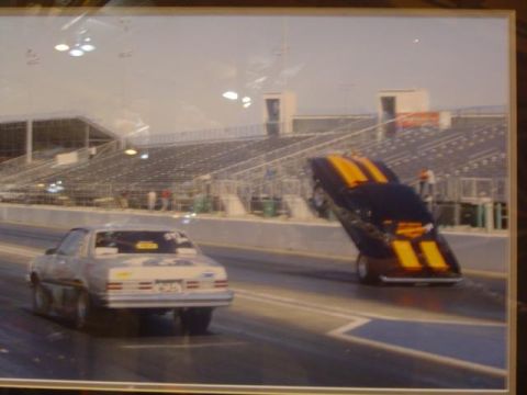 1979 Ford Bronco - Two cars compete on a drag strip, with one performing a wheelie during the race.