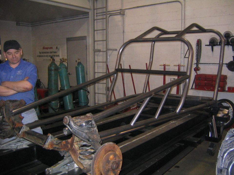 Custom tube chassis in workshop with a man observing