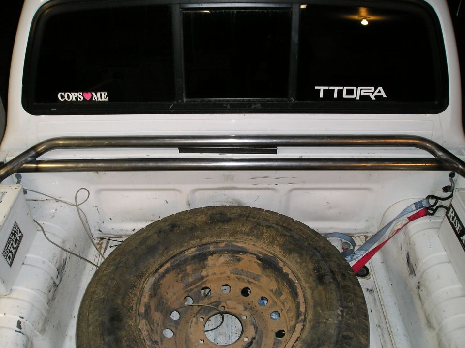 White pickup bed with muddy spare tire and tube rack, TTORA decal on rear window