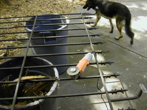 1993 Ford Bronco - A black wrought-iron fence or gate section with spear-tipped pickets laid across two trash cans in a driveway, with an orange corded angle…
