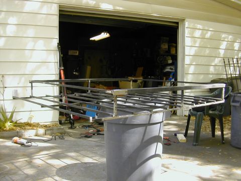 1993 Ford Bronco - A shop-built roof rack fabricated from square steel tubing, propped on trash cans in a driveway outside an open garage while it is being we…