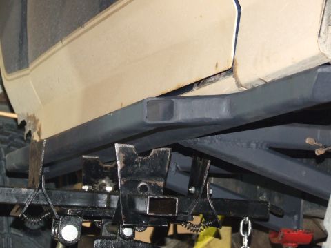 1986 Ford Bronco - Custom rock sliders are mounted to the frame of a vehicle, with visible rust on the lower body panel.