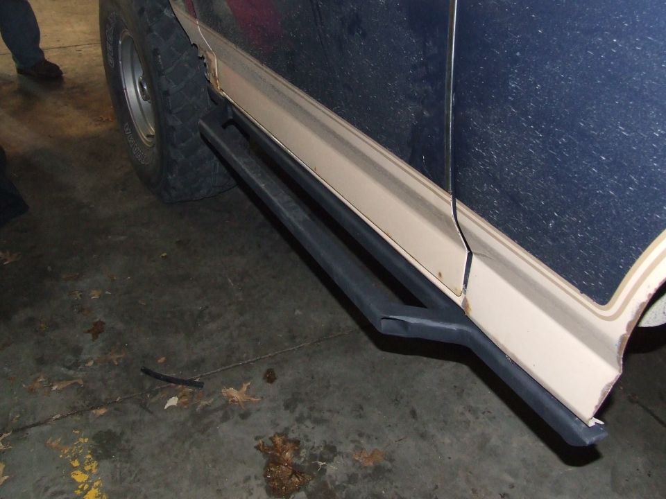 Side view of dark blue SUV with black rock sliders and tan pinstriping