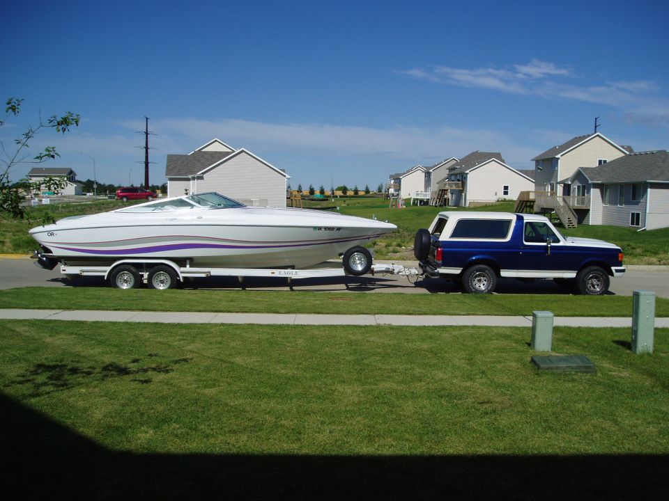 Blue and white Ford Bronco towing a white boat on a trailer