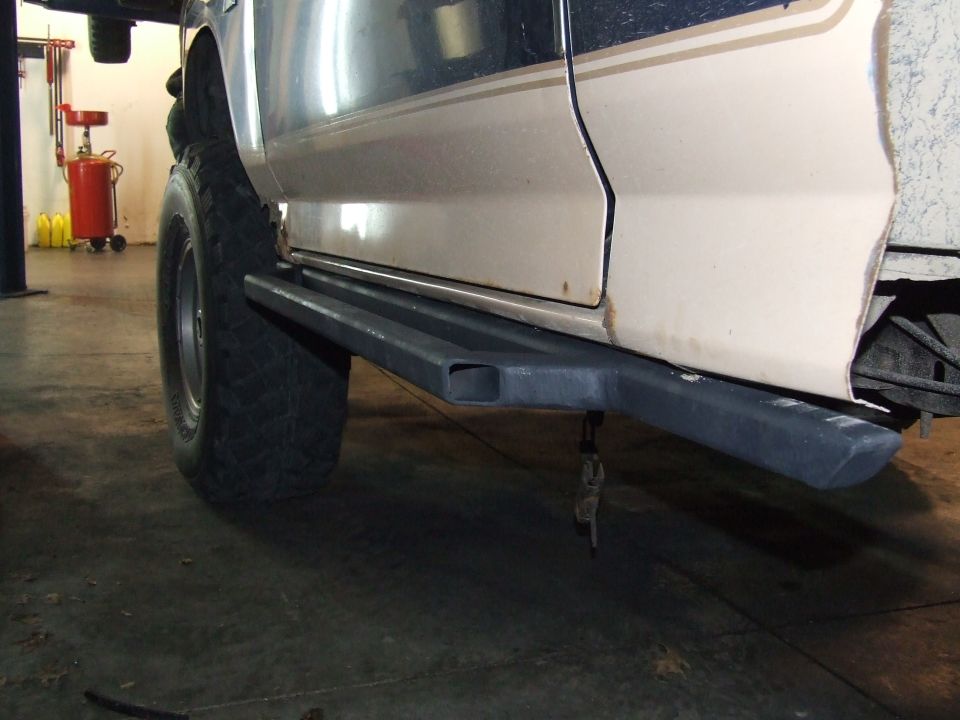 Tan and dark blue Ford Bronco side with custom rock sliders and large tires