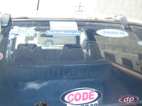 1990 Ford Bronco - vehicle's rear window carries decals including TheWebWheeler.com, an INTERNATIONAL banner, JIMCO and a CODE off-road sticker.