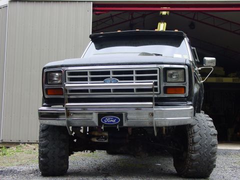 1984 Ford F-250 - This Ford truck features a prominent chrome grille and a brush guard, with oversized tires indicating off-road modifications.