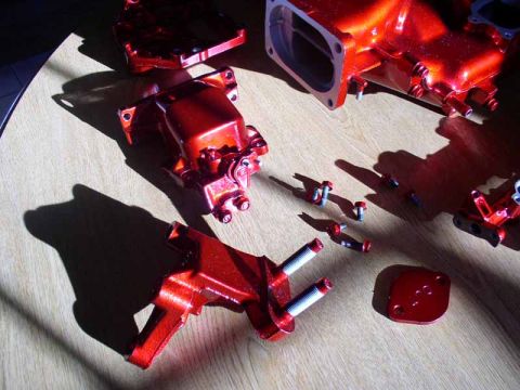 1996 Ford Probe - Various red metallic engine components are laid out on a wooden surface, some with bolts.