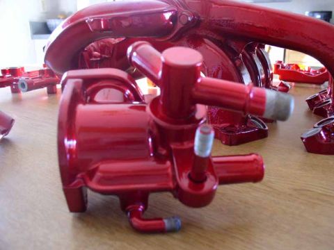 1996 Ford Probe - Red painted engine intake manifold and throttle body components are laid out on a wooden surface, likely awaiting installation.