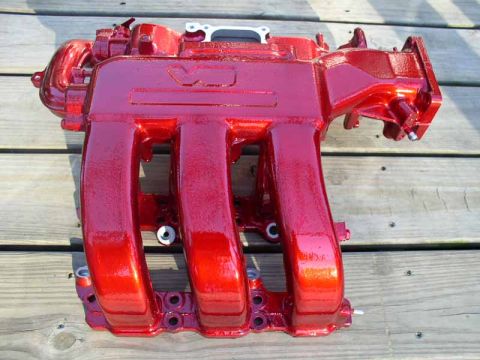 1996 Ford Probe - A red painted intake manifold rests on a weathered wooden surface.