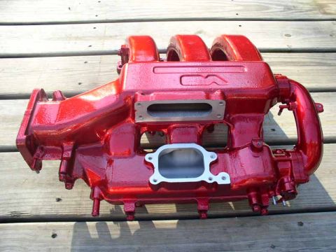 1996 Ford Probe - A red intake manifold is displayed on a weathered wooden surface.