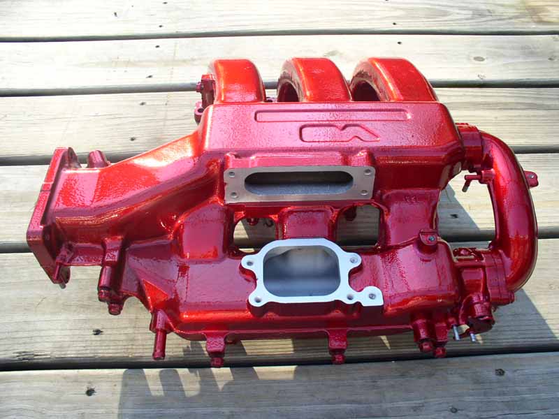 Red intake manifold on wooden planks, showing intake ports and runners