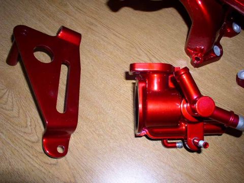 1996 Ford Probe - Two red painted engine parts are laid out on a wooden surface. A watermark for SuperMotors.net is visible.