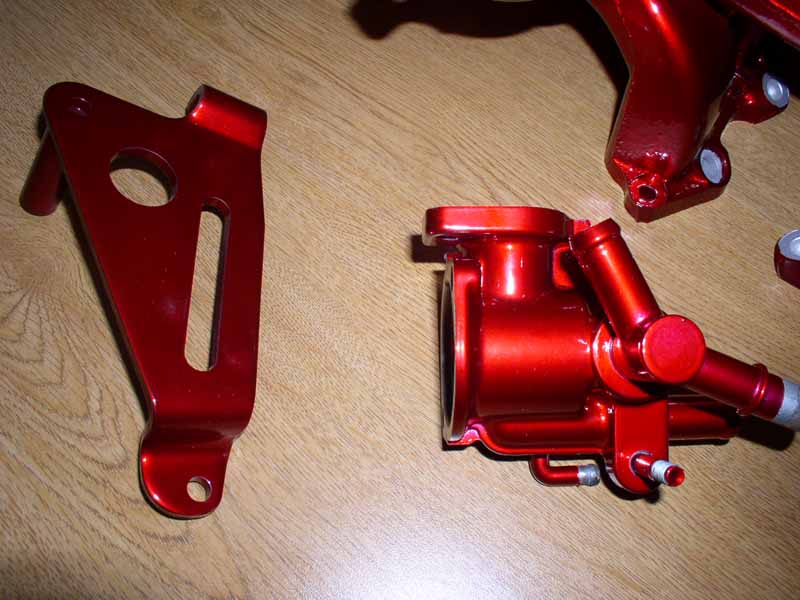 red painted engine bracket and intake manifold on wood surface
