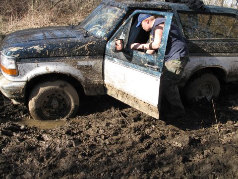 1995 Ford Bronco - Muddy 1995 Ford Bronco with driver's door ajar, stuck in thick mud.