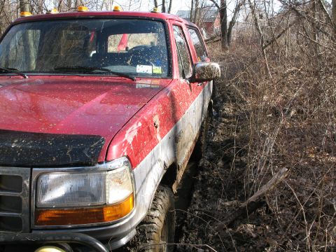 1995 Ford Bronco - This red and silver 1995 Ford Bronco is stuck in a muddy, wooded area.