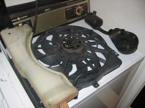 1991 Ford Bronco - A collection of automotive parts, including a radiator fan and coolant reservoir, are displayed on a household appliance.