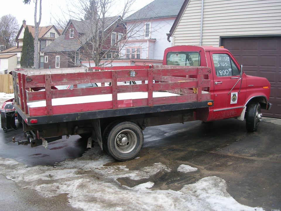 red flatbed truck with wooden sides, writing on window says 14 32 2165 1800