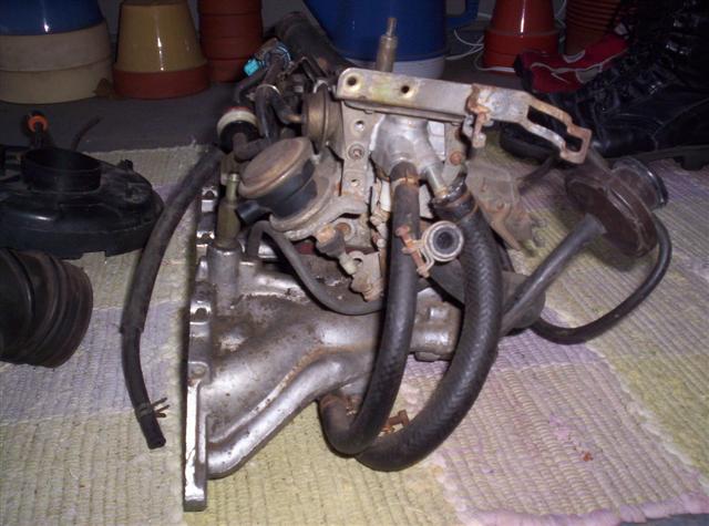 Engine intake manifold with hoses and carburetor components