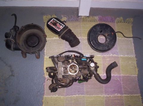1987 Suzuki Samurai - Engine parts including a carburetor and air intake components are displayed on a rug.